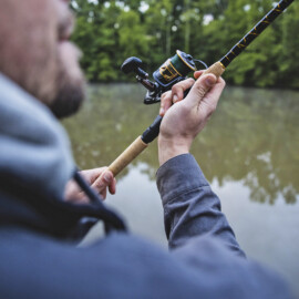 Close-up image of an angler casting an open-faced fishing rod.