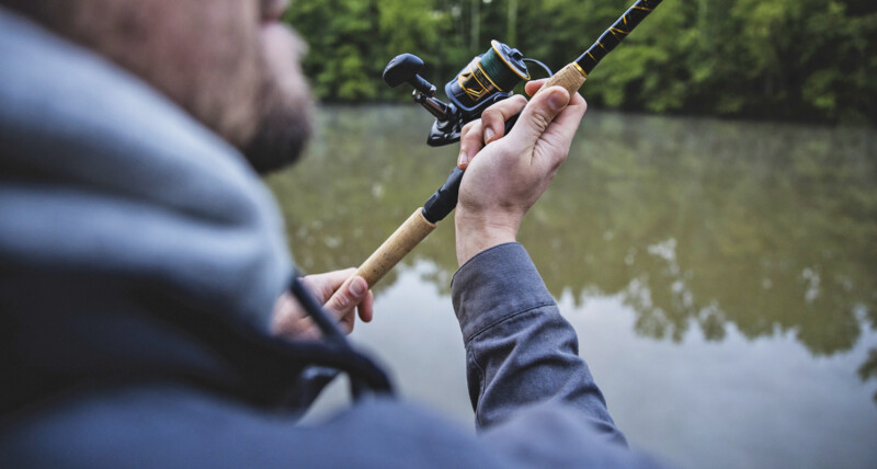 Close-up image of an angler casting an open-faced fishing rod.