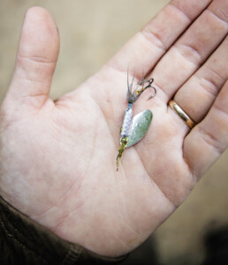 A fishing lure sits in the palm of a hand.