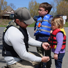 Father fits life jackets for his two children before going out on a boat.