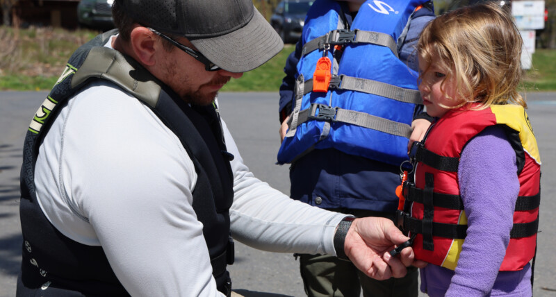 Father fits life jackets for his two children before going out on a boat.