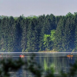 A scenic view of a lake with people paddling