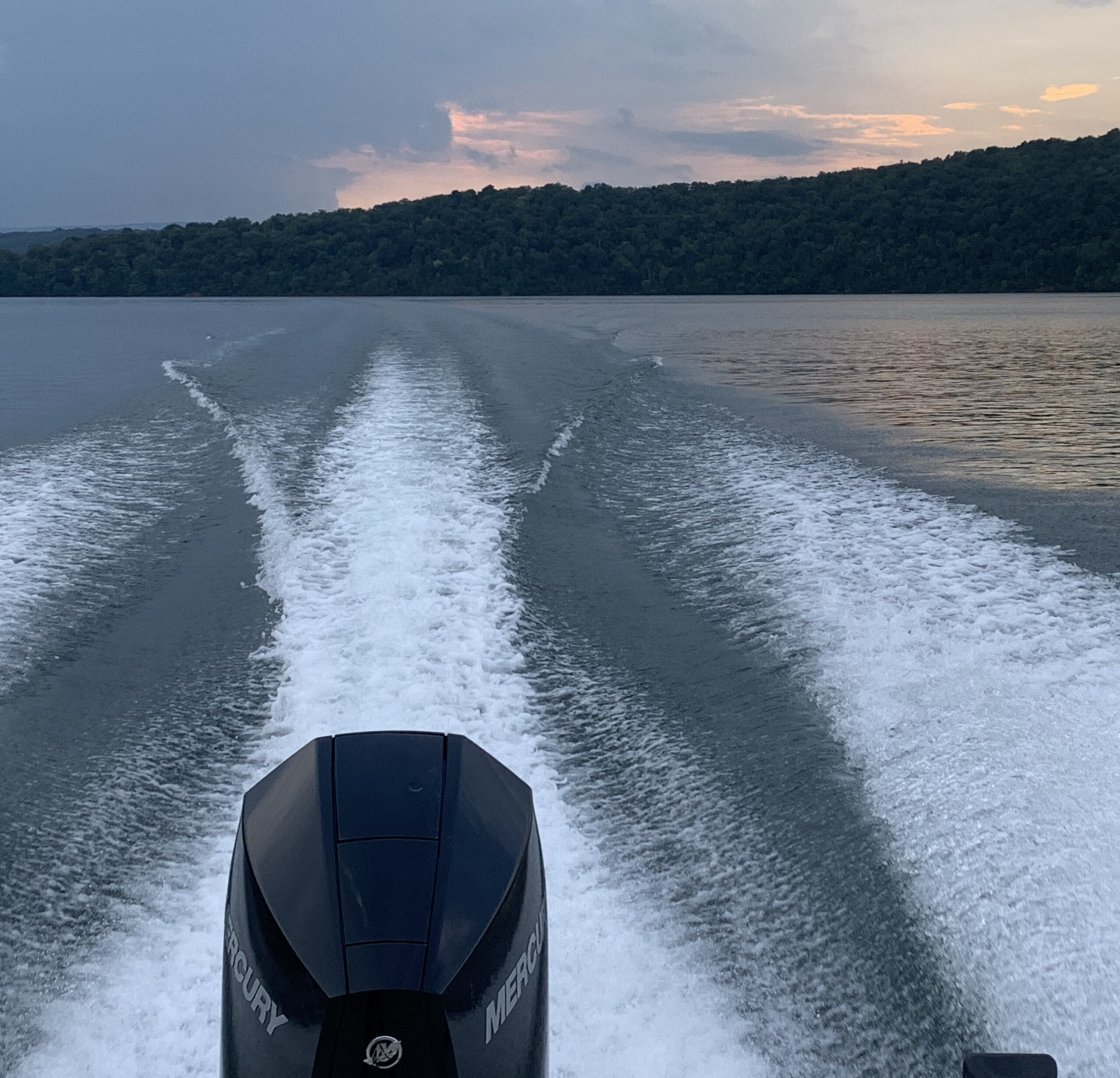 View of a motor on the back of a boat with a scenic sunset on a PA Lake