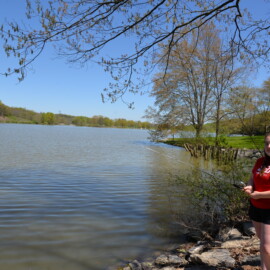 Girl fishing on shore at lake