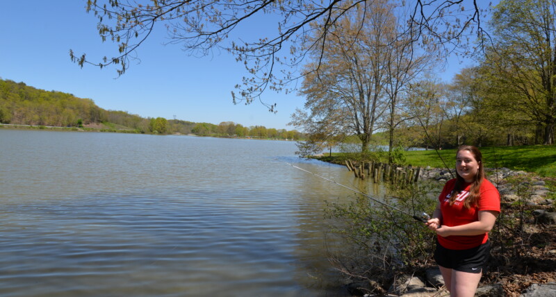 Girl fishing on shore at lake