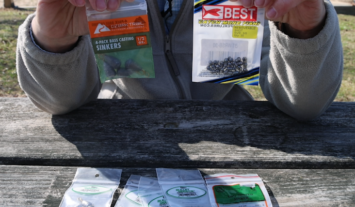 A man's hands holding a bag of bell sinkers and splitshot weights for fishing with other weights laying on a picnic table below