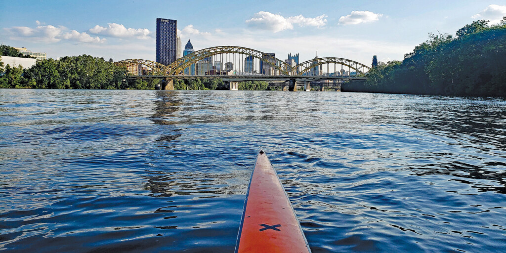 Tip of a long river kayak overlooking a beautiful, scenic view of the Pittsburgh skyline.