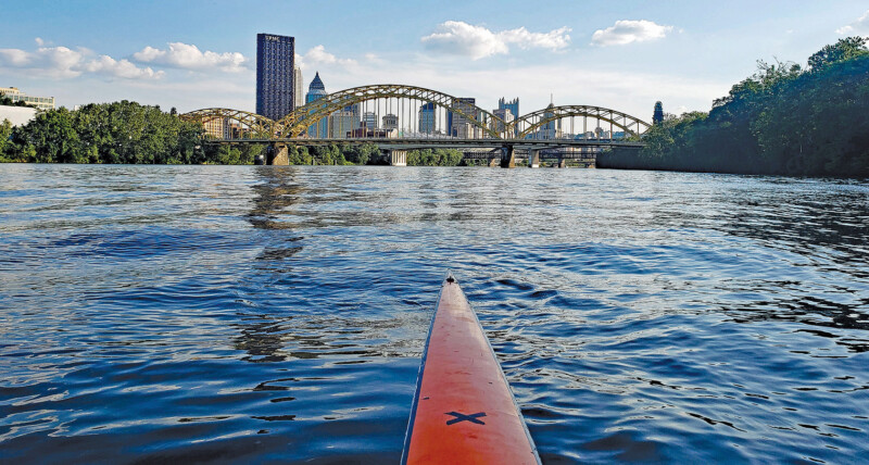 Tip of a long river kayak overlooking a beautiful, scenic view of the Pittsburgh skyline.